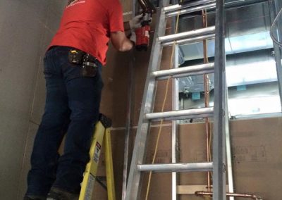 Plombier qui installe de la tuyauterie en hauteur services de plomberie à Joliette - Plomberie le Plomb